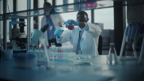 Czarny mężczyzna naukowiec mieszania chemikaliów w laboratorium — Wideo stockowe