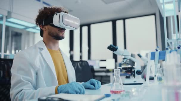 Молодой ученый использует гарнитуру VR, работающую в лаборатории — стоковое видео