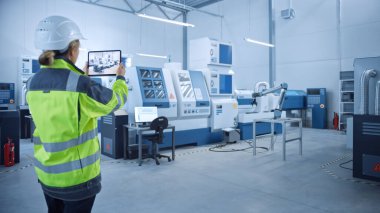 Endüstri 4.0 Modern Fabrika: Kadın Mühendis, Görüntü Atölyesi Haritalama, Yer Düzenleme Artırılmış Gerçekliği ile Dijital Tablet Bilgisayar Kullanıyor. Yüksek teknolojili CNC Makineleri ve robot kolu olan bir tesis