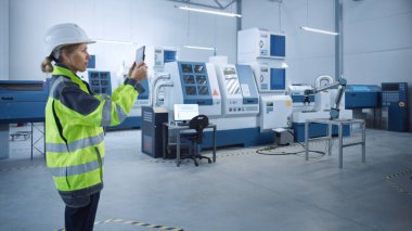 Endüstri 4.0 Modern Fabrika: Kadın Mühendis, Görüntü Atölyesi Haritalama, Yer Düzenleme Artırılmış Gerçekliği ile Dijital Tablet Bilgisayar Kullanıyor. Yüksek teknolojili CNC Makineleri ve robot kolu olan bir tesis