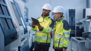 Güvenlik Yelekleri ve Sert Şapkalar Giyen Baş Mühendis ve Proje Yöneticisi, Modern Fabrikada Dijital Tablet Bilgisayar Kullan, Konuş, İyimser CNC Makinesi, Verimliliği Artırmak için Programlama Makinesi