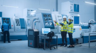 Güvenlik Yelekleri ve Sert Şapkalar Giyen Baş Mühendis ve Proje Yöneticisi, Fabrikada Dijital Tablet Kontrolörü Kullan, Üretim Hattı Verimliliğini Artırmak İçin CNC Makine Programlama Makinesini İyimser Et 