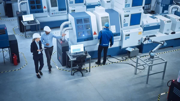 Industria Quattro Fabbrica: Esecutivo femminile e capo ingegnere Ispezione Facility Workshop, Guarda braccio robot che lavora sulla linea di assemblaggio. Macchine e attrezzature CNC di fascia alta. Angolo alto — Foto Stock