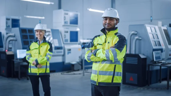 Portrait of Handsome Indian Engineer Wearing Safety Vest and Hardhat Crosses Arms and Smiles. Professional Woman Working in the Modern Manufacturing Factory. Facility with CNC Machinery and robot arm — Stock Photo, Image