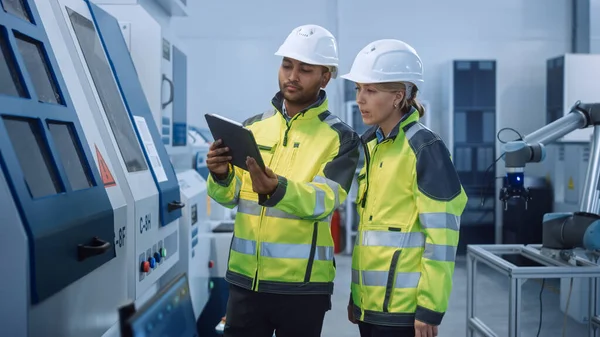 Ingegnere capo e Project Manager che indossa giubbotti di sicurezza e cappelli rigidi, utilizzare computer tablet digitale in fabbrica moderna, parlare, ottimizzare macchinari CNC, macchina di programmazione per aumentare l'efficienza — Foto Stock