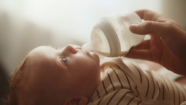Закрыть кормление малыша бутылочкой молока — стоковое видео