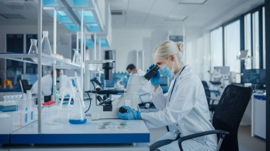 Modern Tıbbi Araştırma Laboratuvarı: Yüz Maskesi Giyen Kadın Bilimadamlarının Mikroskop Altında Portresi, Test Örnekleri Analizi. Gelişmiş Tıp, Mikrobiyoloji Geliştirme Laboratuvarı
