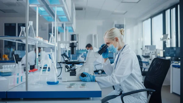 Modern Tıbbi Araştırma Laboratuvarı: Yüz Maskesi Giyen Kadın Bilimadamlarının Mikroskop Altında Portresi, Test Örnekleri Analizi. Gelişmiş Tıp, Mikrobiyoloji Geliştirme Laboratuvarı