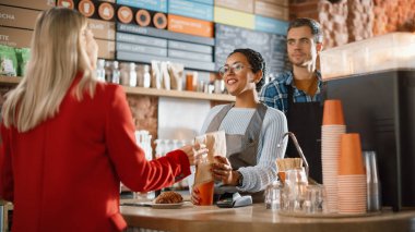 Neşeli Çok Irklı Kadın Akıllı Telefon 'da NFC Teknolojisi Kullanan Müşteriye Ödeme Terminali Veriyor. Müşteri kahvecideki bir baristaya paket kahve ve hamur işi için cep telefonu kullanıyor..