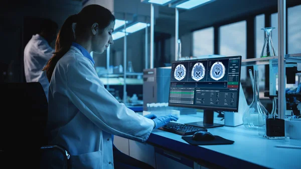 Modern Medical Research Laboratory: Portrait of Female Scientist Working on Computer, Showing MRI Brain Scans. Advanced Scientific Lab for Brain Development. Dark Evening