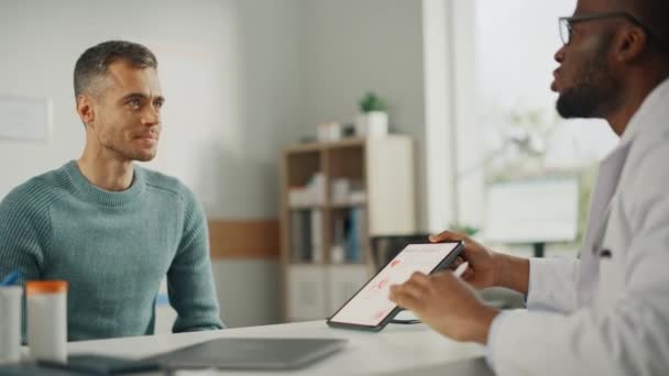 Médico muestra tableta al paciente masculino — Vídeo de stock