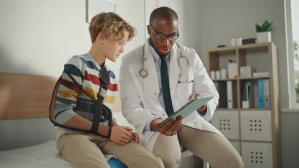 Le docteur parle à un jeune garçon avec un bras cassé à l'hôpital — Video