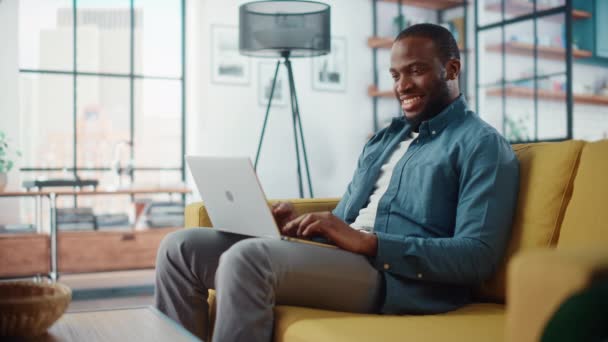 Hombre con ordenador portátil sentado en la sala de estar — Vídeos de Stock