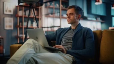 Dizüstü bilgisayarlı erkek Oturma odasında oturuyor