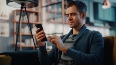 Akıllı telefonlu bir erkek Oturma odasında oturuyor