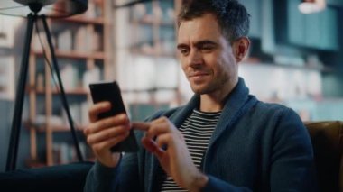 Akıllı telefonlu bir erkek Oturma odasında oturuyor