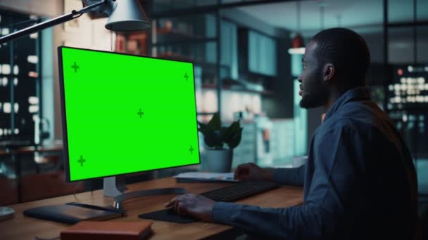 Masculino trabalhando no computador desktop com tela verde na sala de estar — Vídeo de Stock