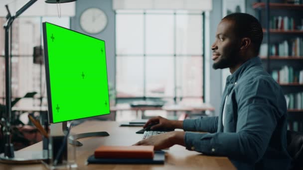 Masculino trabalhando no computador desktop com tela verde na sala de estar — Vídeo de Stock