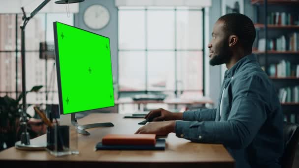 Homme travaillant sur ordinateur de bureau avec écran vert dans le salon — Video