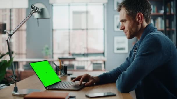 Erkek, oturma odasında yeşil ekranlı dizüstü bilgisayarda çalışıyor. — Stok video