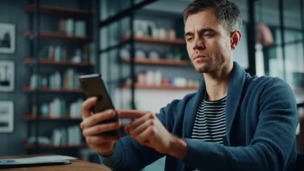 Man med smartphone sitter i vardagsrummet — Stockvideo
