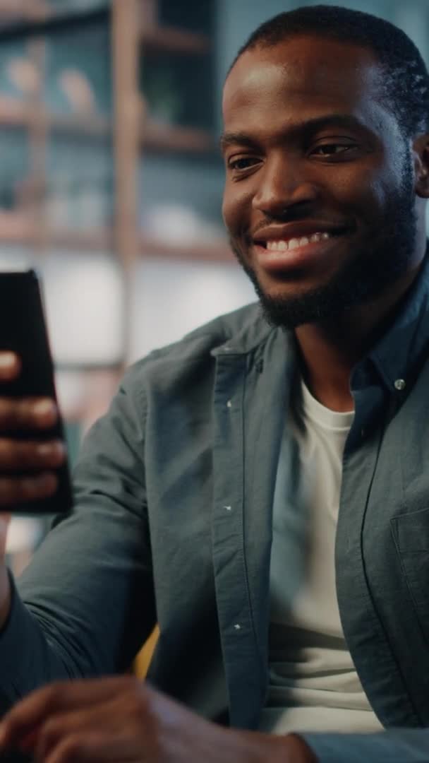 Vertical tiro masculino com Smartphone sentado na sala de estar — Vídeo de Stock