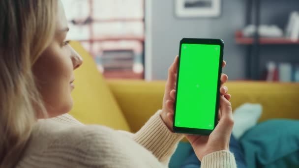 Kobieta za pomocą smartfona z zielonym ekranem w salonie — Wideo stockowe