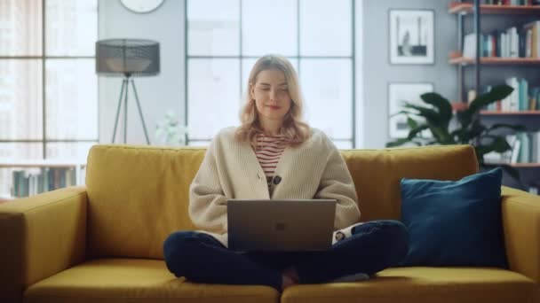 Žena s notebookem sedí na pohovce v obývacím pokoji — Stock video