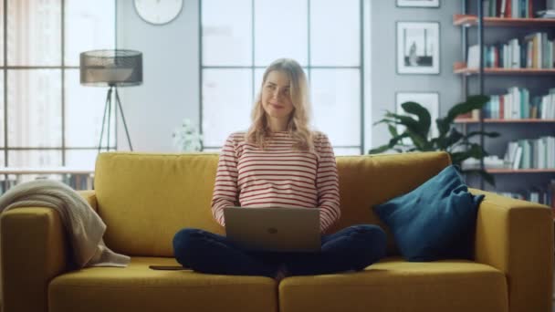 Kobieta z laptopem siedzi na kanapie w salonie — Wideo stockowe