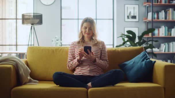 Female with Smartphone Sitting on Sofa in Living Room — Stock Video