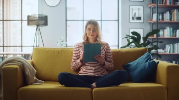 Feminino com Tablet sentado no sofá na sala de estar — Vídeo de Stock