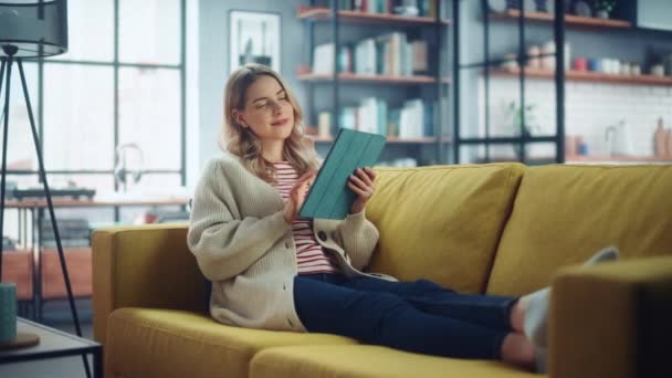 Žena s tabletou sedí na pohovce v obývacím pokoji — Stock video