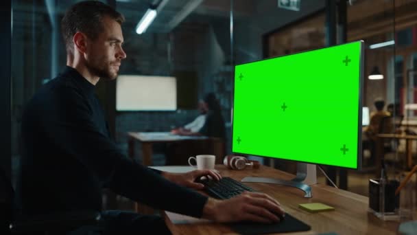 Uomo lavora su computer con schermo verde in ufficio creativo — Video Stock