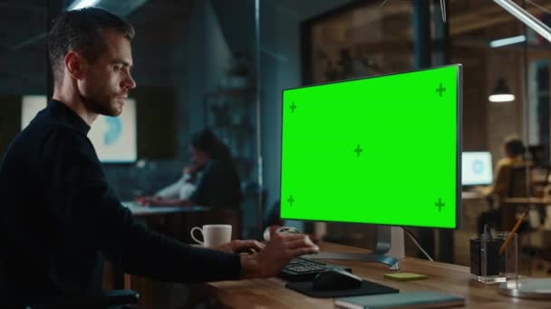 Uomo lavora su computer con schermo verde in ufficio creativo — Video Stock