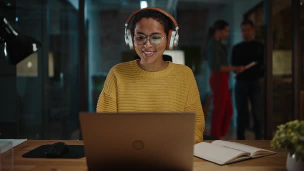 Жіночий менеджер в навушниках використовує ноутбук у творчому офісі — стокове відео