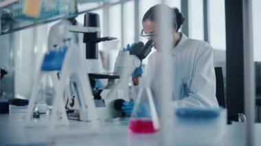 Mikroskop kullanan büyük bir tıp laboratuarı bilimcisi.