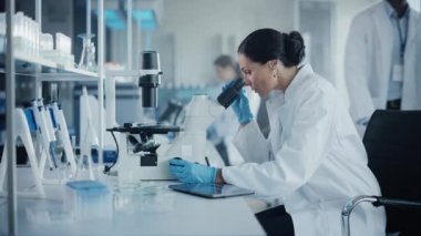 Mikroskop kullanan büyük bir tıp laboratuarı bilimcisi.