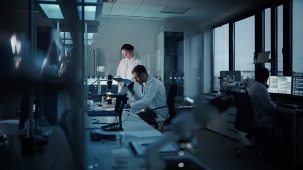 Två forskare arbetar i laboratoriet på natten — Stockvideo