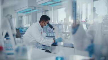 Laboratuvarda Mikroskop altında Maske Giyen Bilim adamı