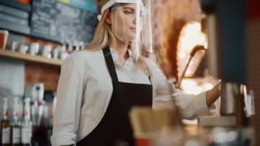 Kafe çalışanı, yüz kalkanı takıyor.