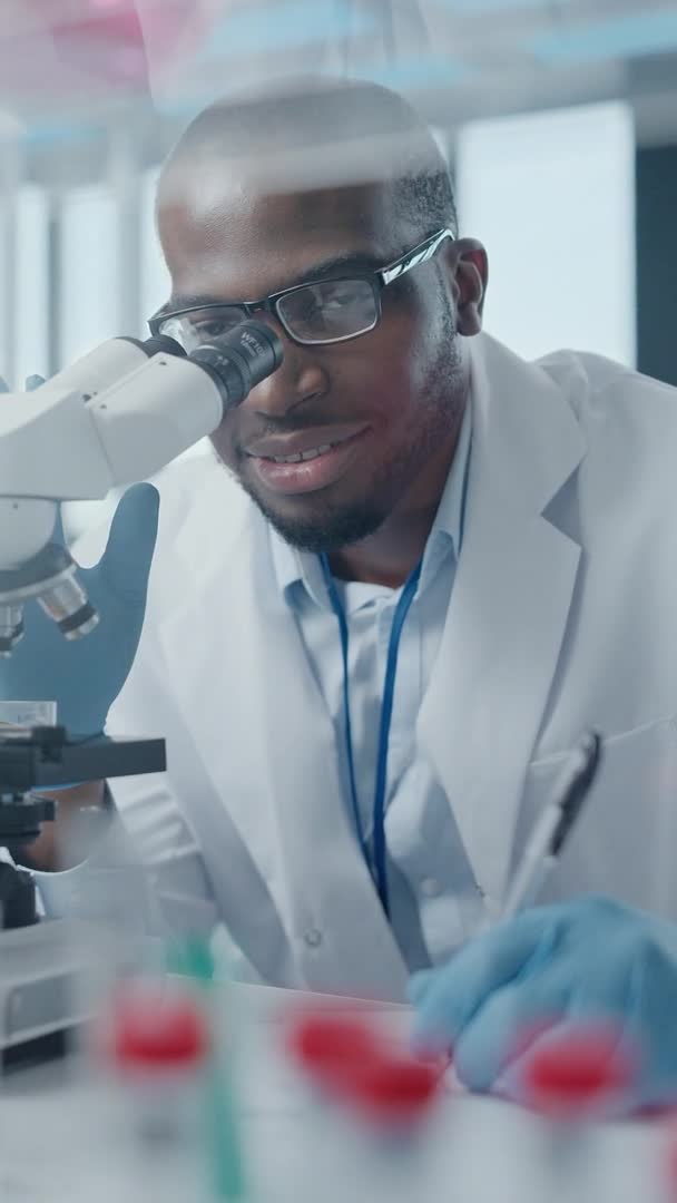 실험실에서 현미경으로 관찰하고 있는 수직 비디오 과학자 — 비디오