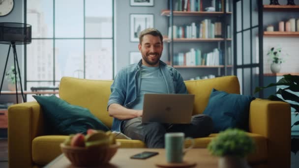 Hombre con ordenador portátil sentado en la sala de estar — Vídeo de stock