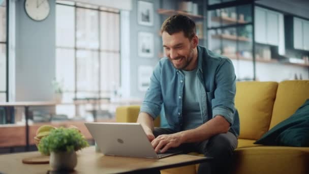 Man met laptop zit in de woonkamer — Stockvideo