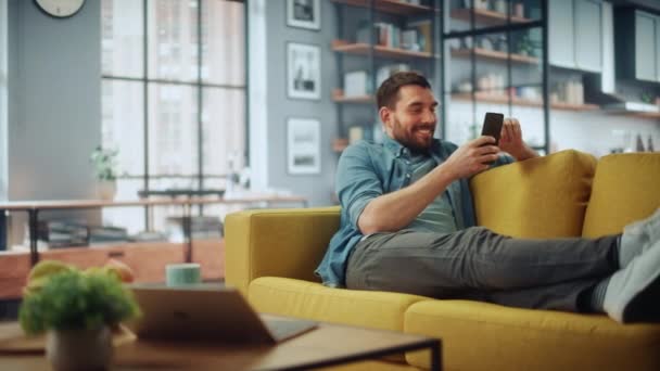 Hombre usando Smartphone en la sala de estar — Vídeos de Stock