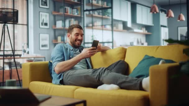 Hombre usando Smartphone en la sala de estar — Vídeo de stock