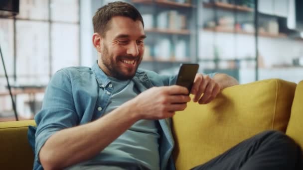 Αρσενικό χρησιμοποιώντας Smartphone στο σαλόνι — Αρχείο Βίντεο