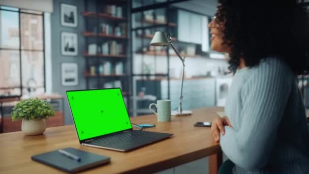 Vrouw op video oproep op laptop met groen scherm in de woonkamer — Stockvideo