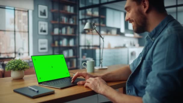 Hombre usando el ordenador portátil con pantalla verde en la sala de estar — Vídeos de Stock