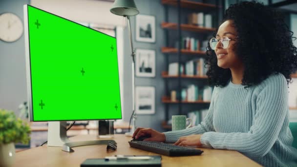 Vrouw met behulp van computer met groen scherm in de woonkamer — Stockvideo