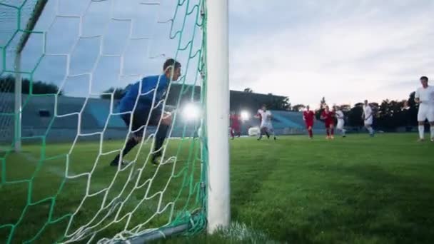 Side View Goleiro em pé em metas tentando pegar bola chutada atacando equipe, mas falhando — Vídeo de Stock